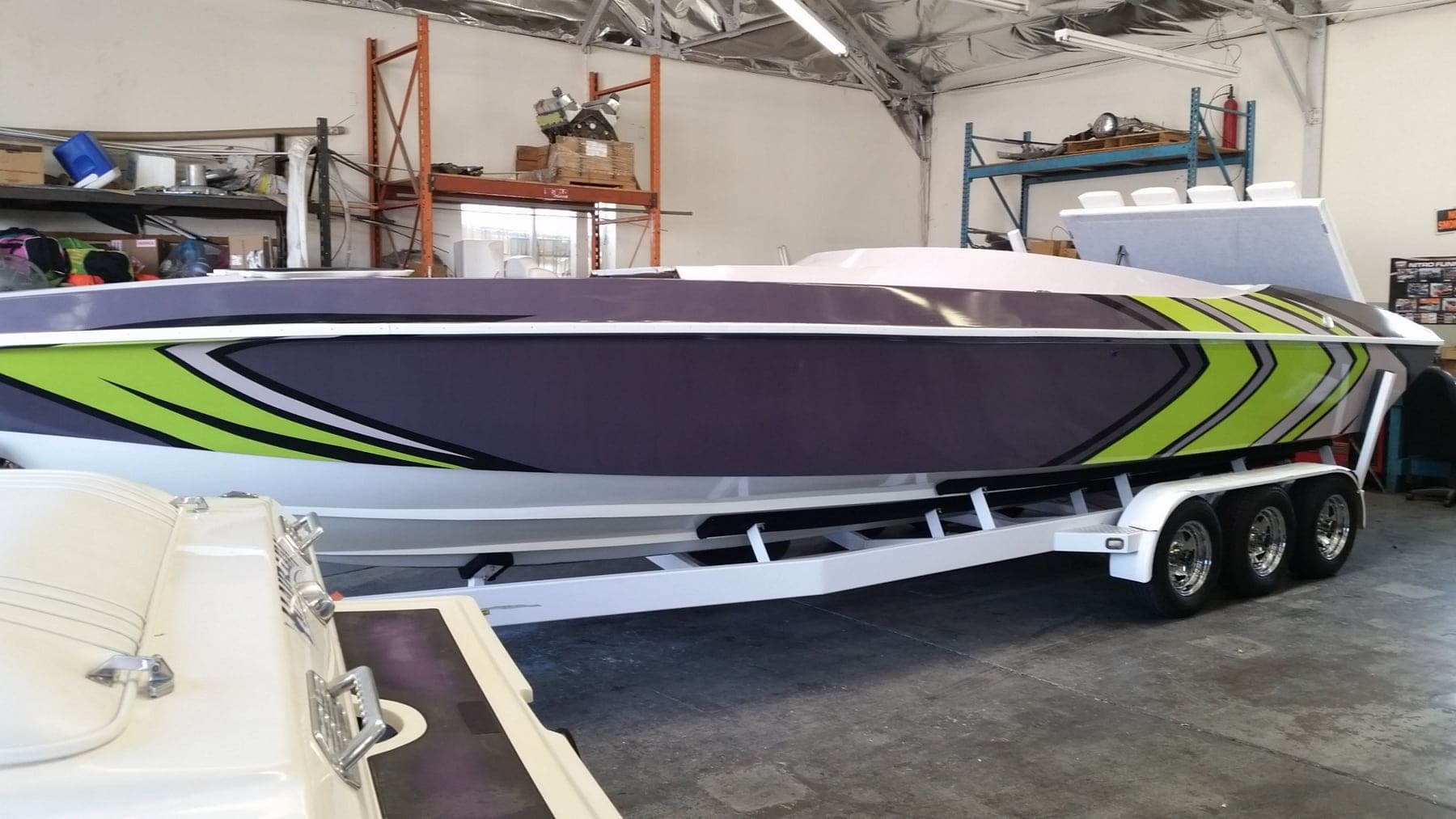 Powerboat on a trailer wrapped in purple, green, and grey hull graphics