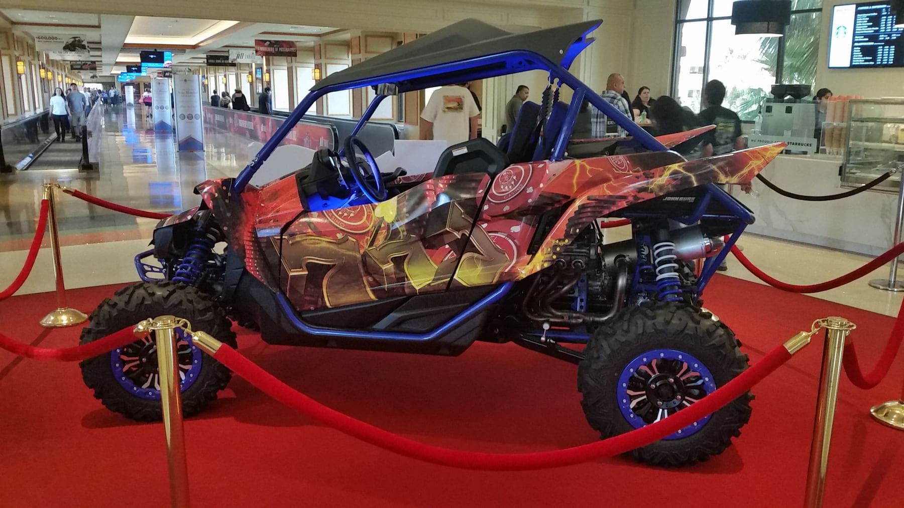 Side-by-side off-road UTV wrapped in a full-color custom graphic, displayed on a red carpet