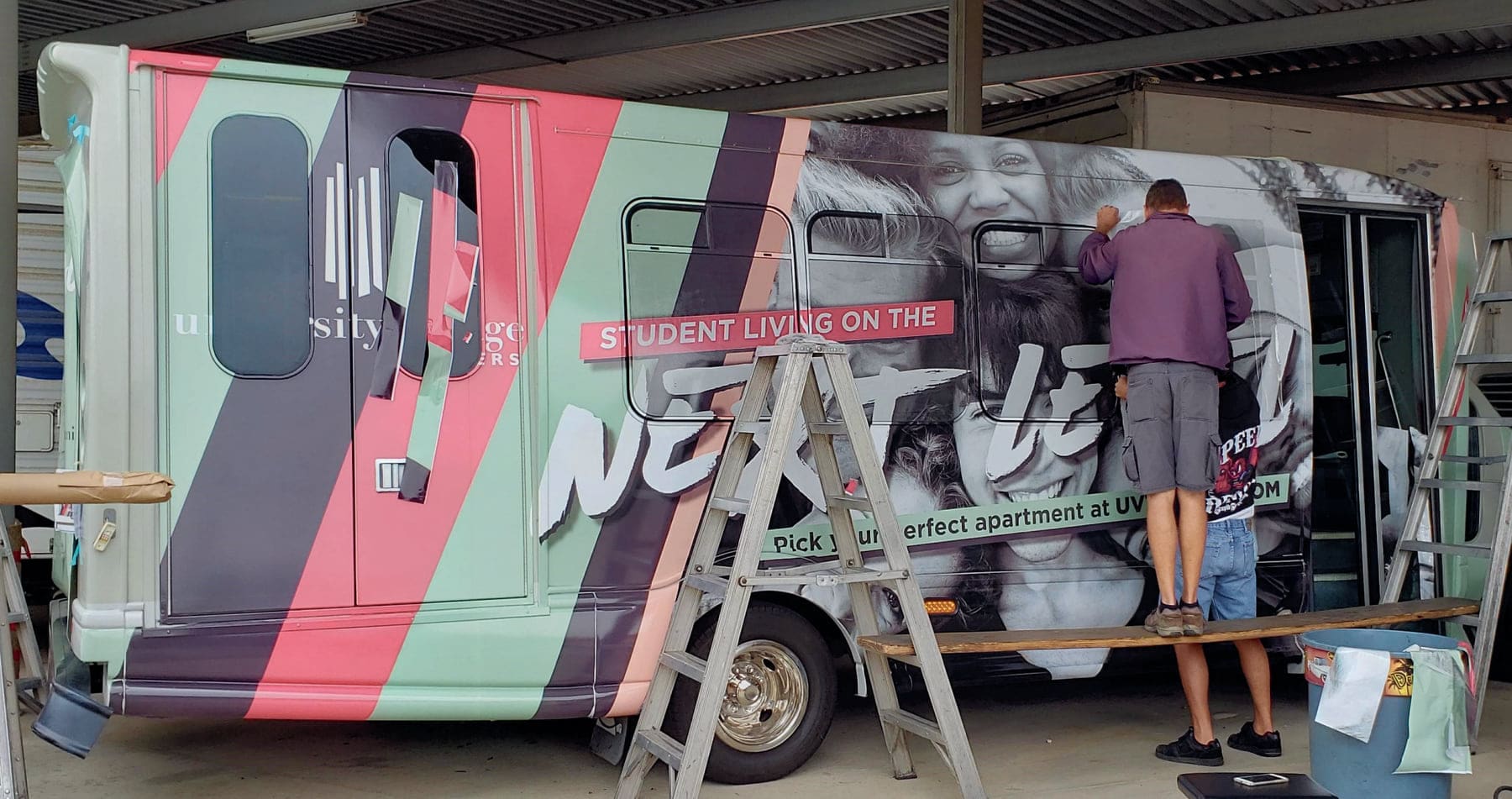 Installer applying printed graphics to a shuttle bus at the customer's location