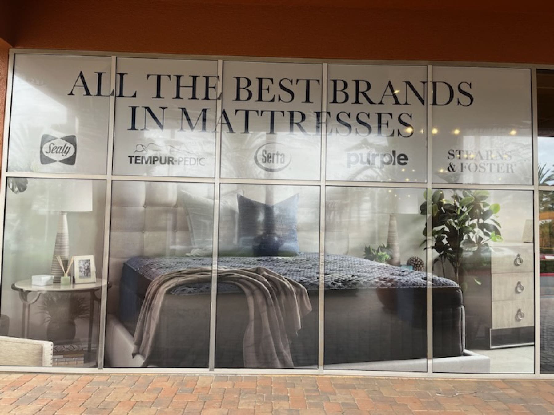Retail storefront glass with printed lettering and brand logos across the window