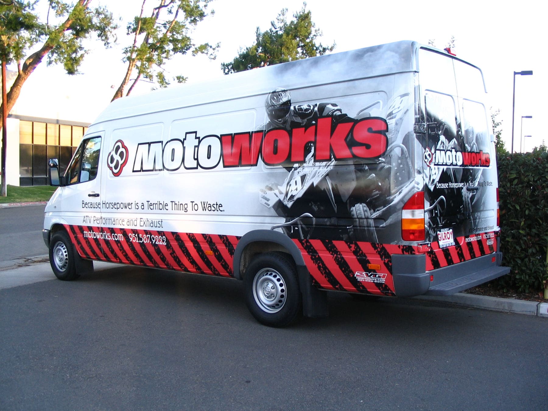 High-roof cargo van wrapped in red and black powersports graphics with action photography along the side