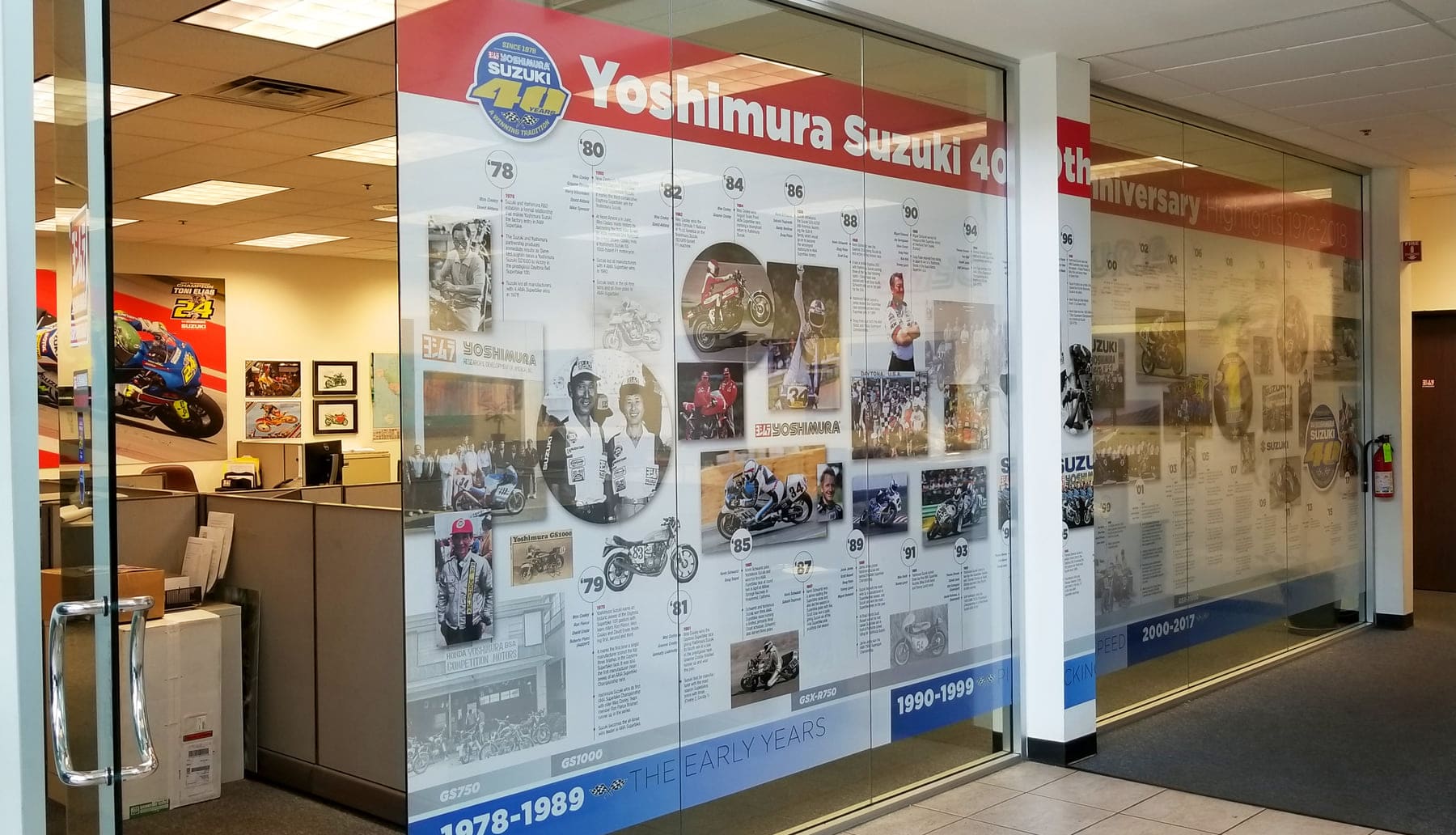 Office glass wall covered with a printed anniversary timeline graphic that screens the workspace behind it