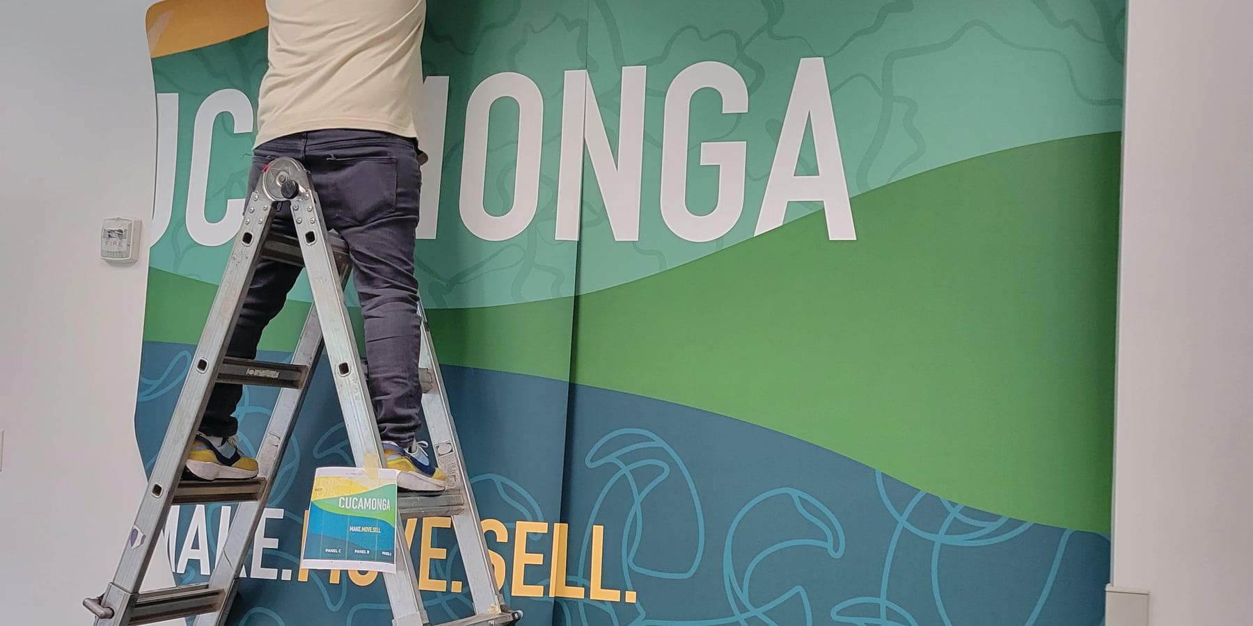 Installer on a ladder smoothing a printed wall graphic into place